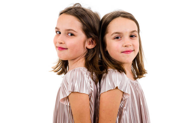 istock Identical twin girls are turned facing back to back. 1140342040