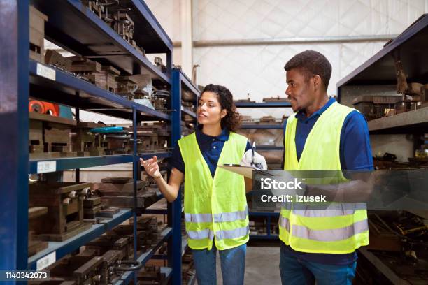 Production Workers Examining Equipment On Racks Stock Photo - Download Image Now - 25-29 Years, 30-34 Years, Adult