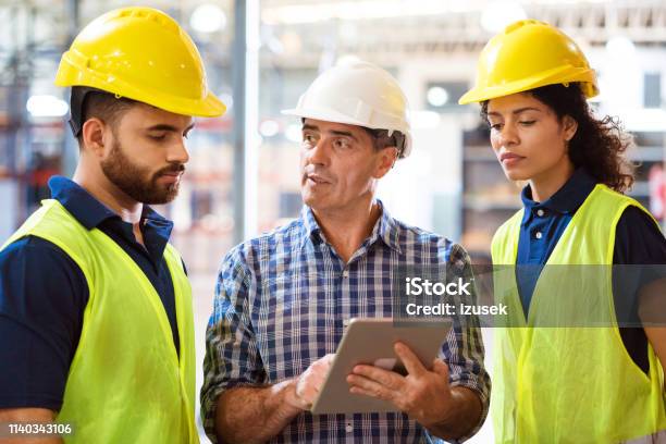 Man Discussing Over Digital Tablet With Colleagues Stock Photo - Download Image Now - Expertise, Factory, Technology