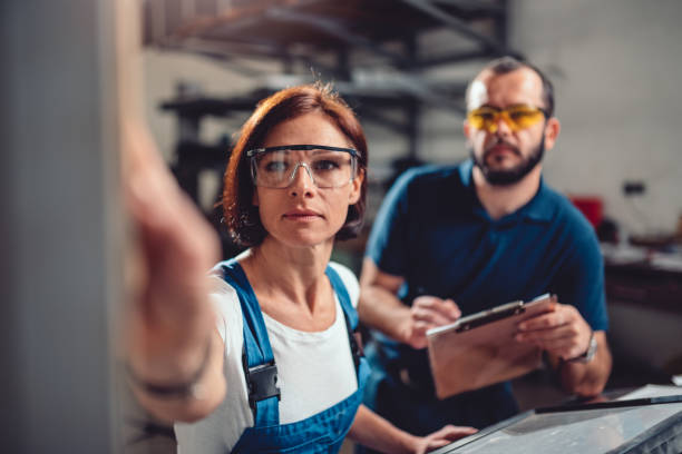 Female worker operate machine in factory Female worker operate CNC machine while supervisor monitoring procedure repairperson occupation stock pictures, royalty-free photos & images