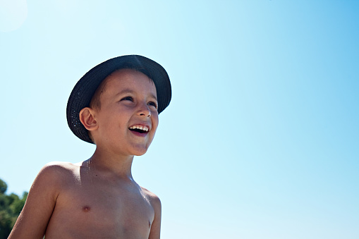 cute boy at the beach, wearing a hat, for sun and heat protection