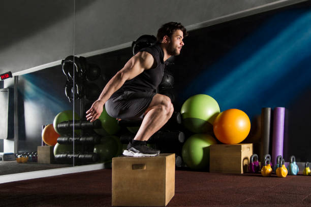 Side View of Young Athlete is Doing Box Jumping in Gym