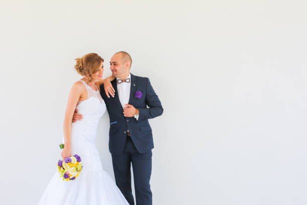 Beautiful wedding couple posing in front of white wall
