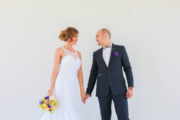 istock Beautiful wedding couple posing in front of white wall 1140351349