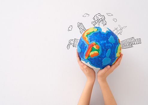 Child holding planet in hands against white background. Earth day holiday concept.