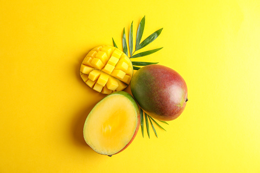 Fresh tropical ripe mango on color background, top view