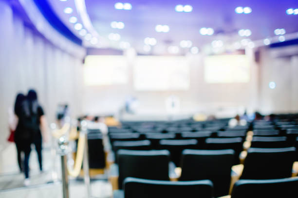 Blurry of auditorium for shareholders' meeting or seminar event,  some business people walking and looking for a seat in conference hall