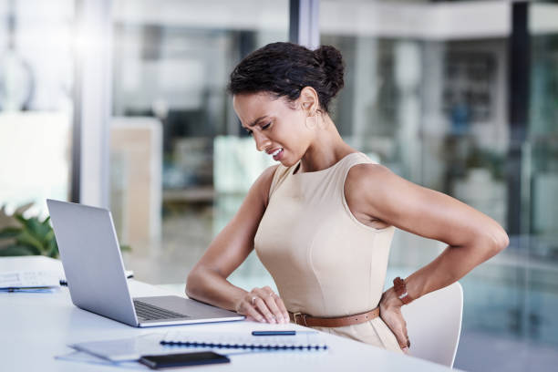 Stress, the career destroyer Shot of a young businesswoman experiencing back pain while working in a modern office office back pain stock pictures, royalty-free photos & images