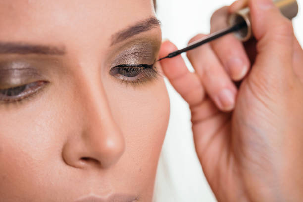 istock Make up artist applying eyeliner on female client's eyelids 1140357186