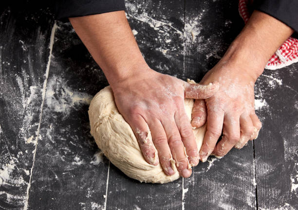 istock baker kneads white wheat flour dough on a black wooden table 1140358160