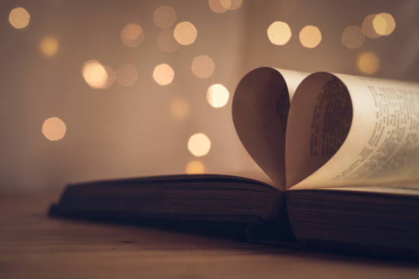 istock Book pages folded into a heart shape with blurred light bokeh background 1140363012