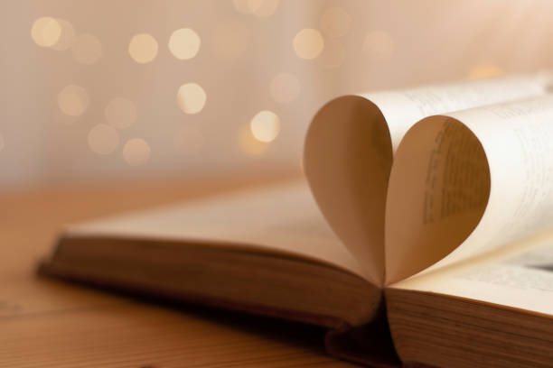 istock Book pages folded into a heart shape with blurred light bokeh background 1140363025