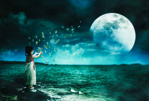 istock Asian girl playing with soap bubbles. Super moon behind partial cloud on sky. 1140365027
