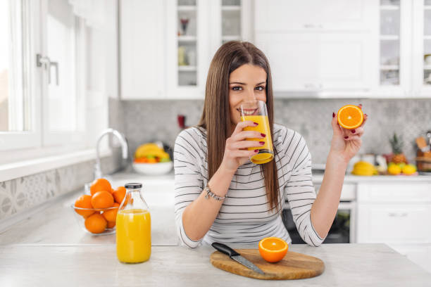 istock Close up Attractive young Woman drinking juice while Holding Sliced Orange Fruit. 1140365664