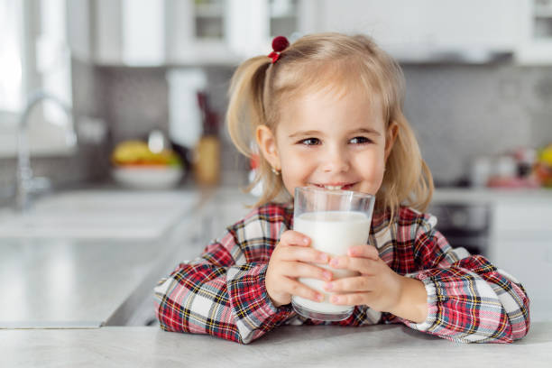 Female child drinking glass of milk stock photo