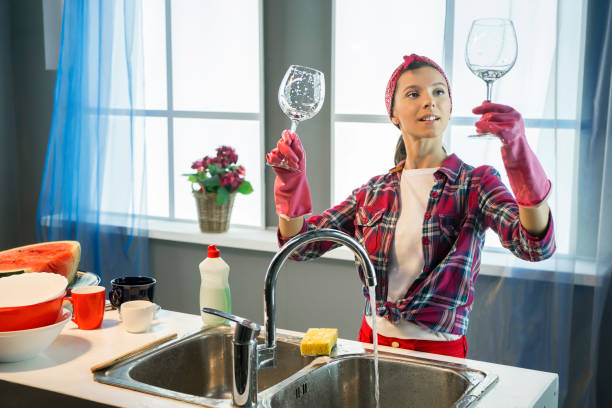 Woman washes wineglasses in kitchen stock photo