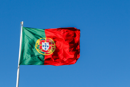 Portugal flag blowing in the wind on blue sky background