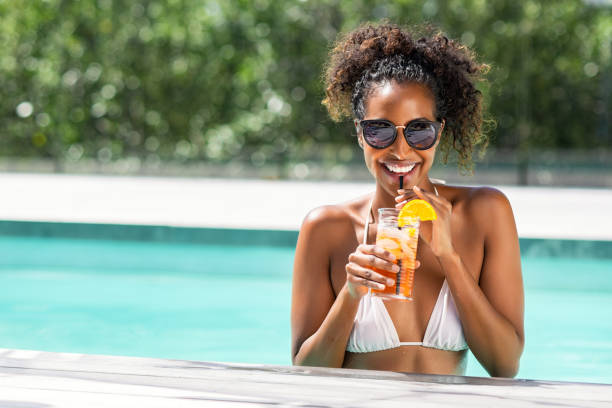 femme de beauté de mode dans le cocktail de boisson de piscine - rebord de piscine photos et images de collection