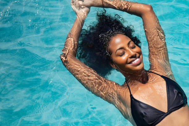 glückliche frau entspannt im schwimmbad - swimming pool women floating on water bikini stock-fotos und bilder