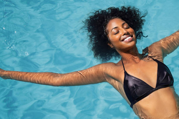donna africana che si rilassa in piscina - cheerful swimming pool happiness resort swimming pool foto e immagini stock