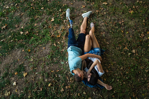 Drone point view  of young couple in love  lying on grass, cuddling and  embracing