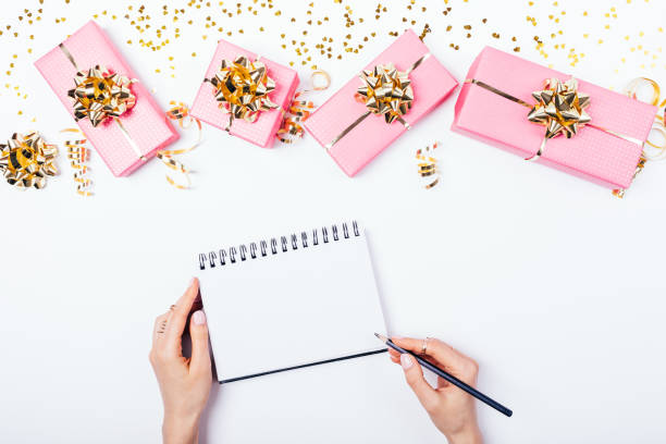 istock Female's hands writing in blank notepad near festive bright pink gift 1140384924