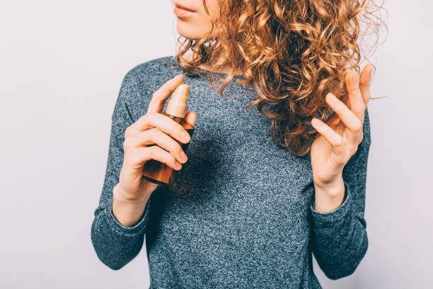 Young woman holding bottle with nutritional oil Young woman holding bottle with nutritional oil applying on her curly brown hair. Female's hands using cosmetic serum to prevent split ends. wiping tears stock pictures, royalty-free photos & images