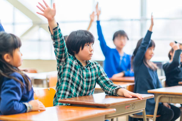 istock Group of elementary school children raising their hands in classroom 1140387640