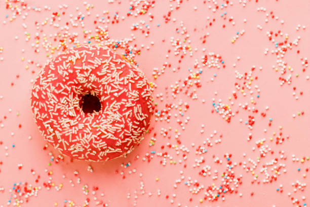 istock Coral donut lying on pink. Donut decorated with icing on pink. 1140390752