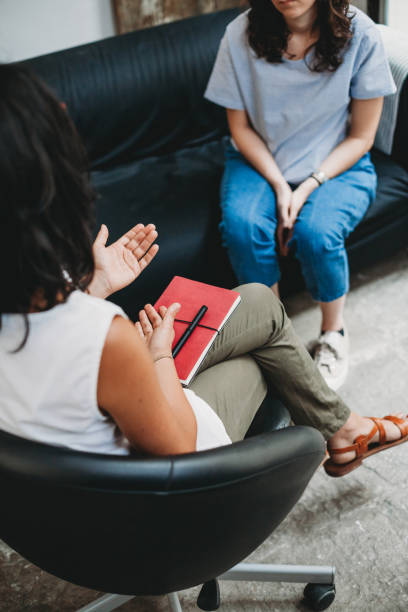 sessione di psicoterapia, donna parla con la sua psicologa in studio - home interior young adult professional occupation vertical foto e immagini stock