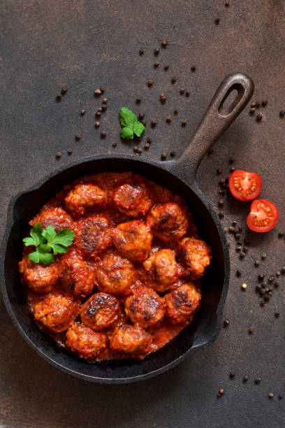 Meatballs in sweet and sour tomato sauce on the kitchen table. Top view stock photo