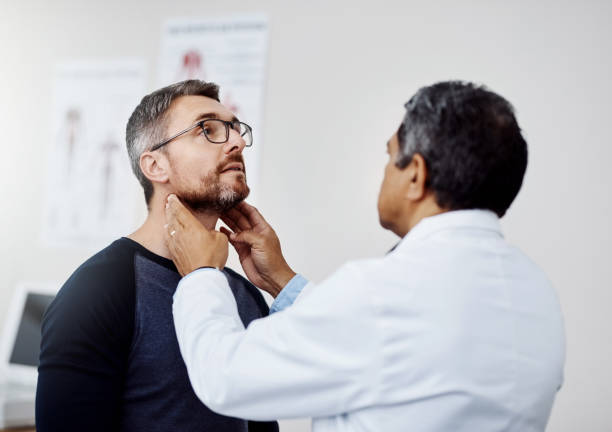 I just need you to take a deep breath for me Shot of a confident mature male doctor doing a checkup on a patient inside of a hospital during the day neck stock pictures, royalty-free photos & images