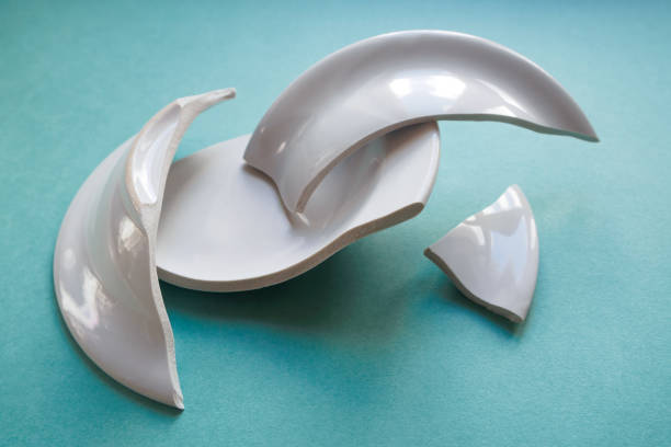 istock pile of broken white plate on green background 1140396549