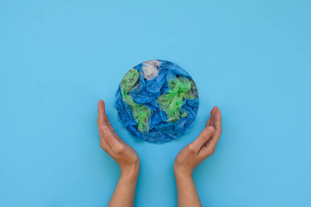 hände halten planet erde aus plastik-einweg-verpackungen auf blauem hintergrund. retten sie die welt, kreativ, umweltverschmutzung oder world earth day konzept. top view - globe earth world map human hand stock-fotos und bilder