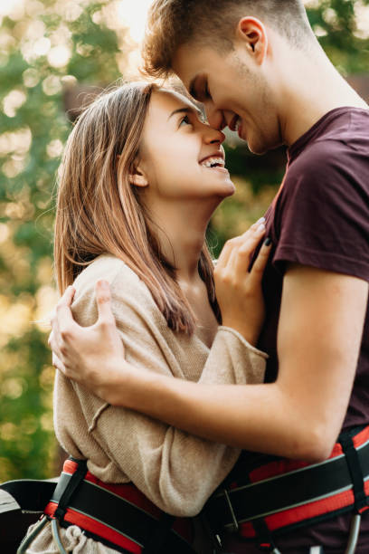 portret z boku niesamowitej pary obejmującej i śmiejącej się na platformie zipline wyposażonej przed podszewką zip. - zip lining zdjęcia i obrazy z banku zdjęć