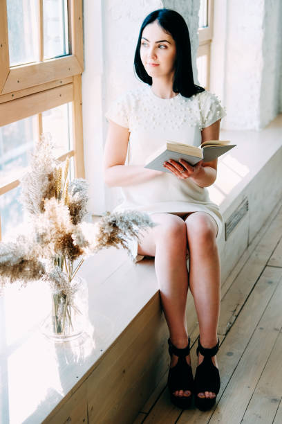 istock Young student woman with long black hair sitting in the class reading a book 1140407277