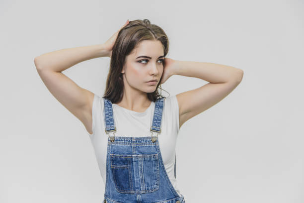 istock A young beautiful girl stands on a gray background. Having put his hands on the hair looking sideways, has beautiful blue eyes. 1140407498