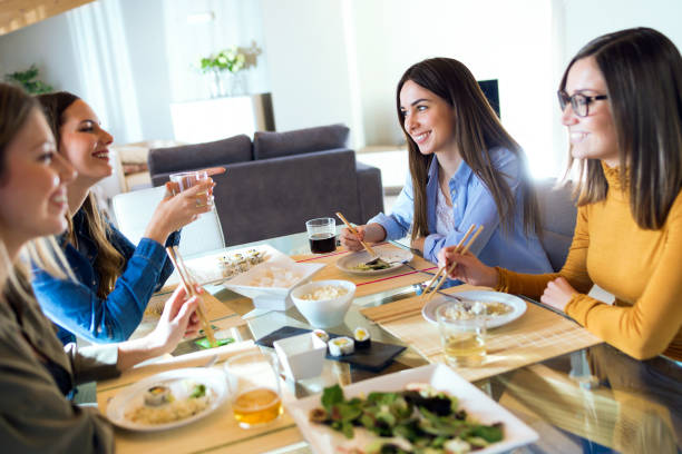 cuatro hermosas jovencitas comiendo comida japonesa en casa. - sushi restaurant fish japanese culture fotografías e imágenes de stock
