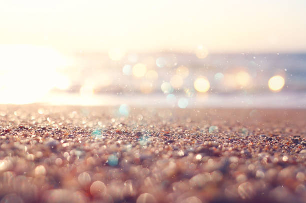 background image of sandy beach and ocean waves with bright bokeh lights