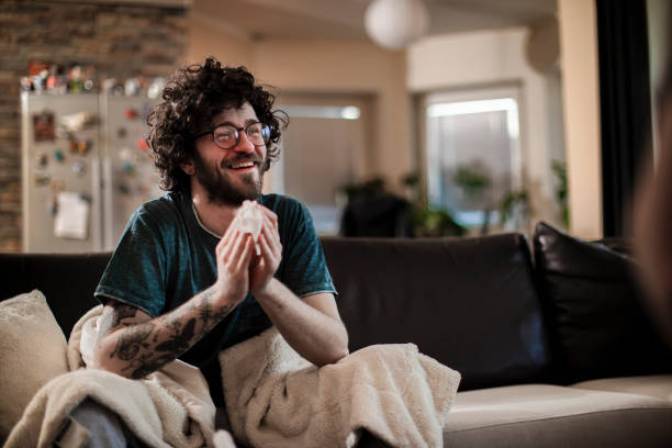 istock Man sitting in living room blowing nose 1140416612