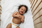 Laughing baby boy lying in a crib wearing a diaper