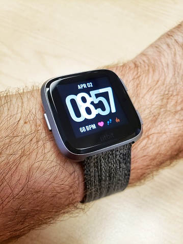 Fitbit versa fitness tracker and smartwatch on a Caucasian male wrist. Used for fitness and health tracking. Close-up