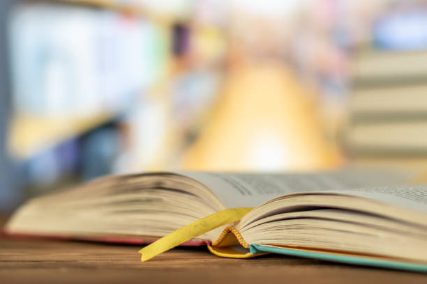Education learning concept with opening book or textbook in old library, stack piles of literature text Education learning concept with opening book or textbook in old library, stack piles of literature text academic archive on reading desk and aisle of bookshelves in school study class room background opportunity dictionary definition stock pictures, royalty-free photos & images