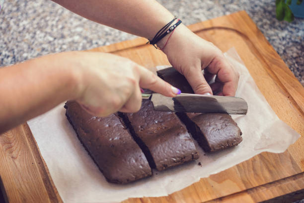 Young woman cutting freshly baked chocolate brownies at home