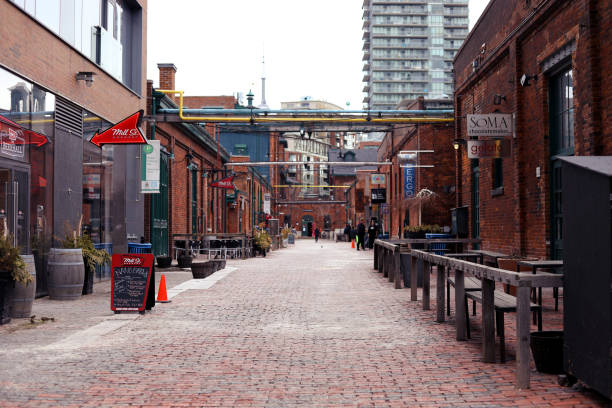 Toronto, Canada - August 23, 2024: Visitors relax outside St. Lawrence Market on Market Street with no traffic. Looking south on Market Street from Front Street East in Old Toronto. Summer afternoon with humid ity.