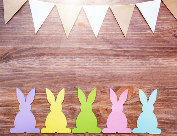 istock Easter card with rabbits and garland flags on wooden background 1140425742