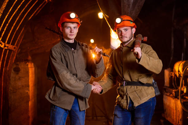 istock Two young guys in working uniform and protective helmets, shaking hands.Miners 1140429962