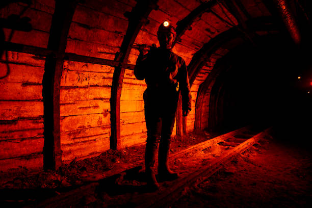 istock A man in work overalls and a helmet with a jackhammer on his shoulder is standing on the rails. Silhouette in red. Miner 1140430723