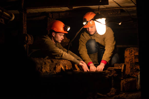 istock Two young guys in a working uniform and protective helmets, sitting in a low tunnel. Miners 1140430785