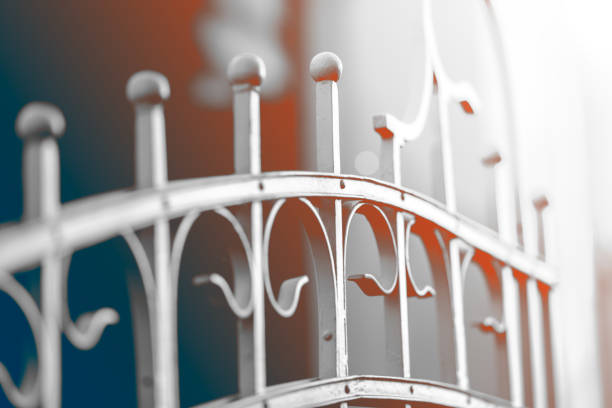New fence made of painted metal rods with concrete posts. The background is blurred.